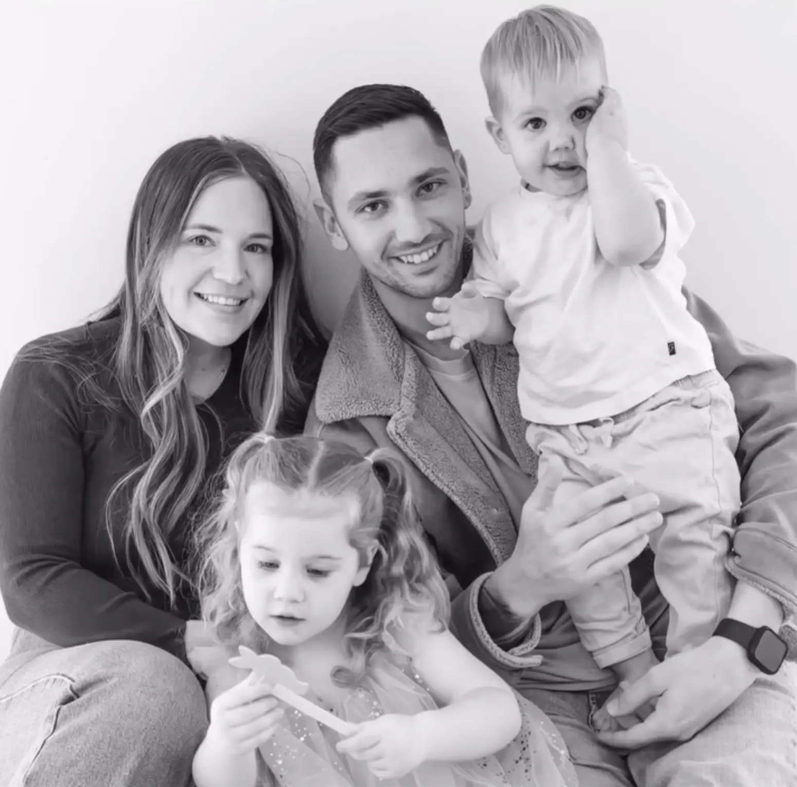 Black and white studio portrait of a family of four sitting together