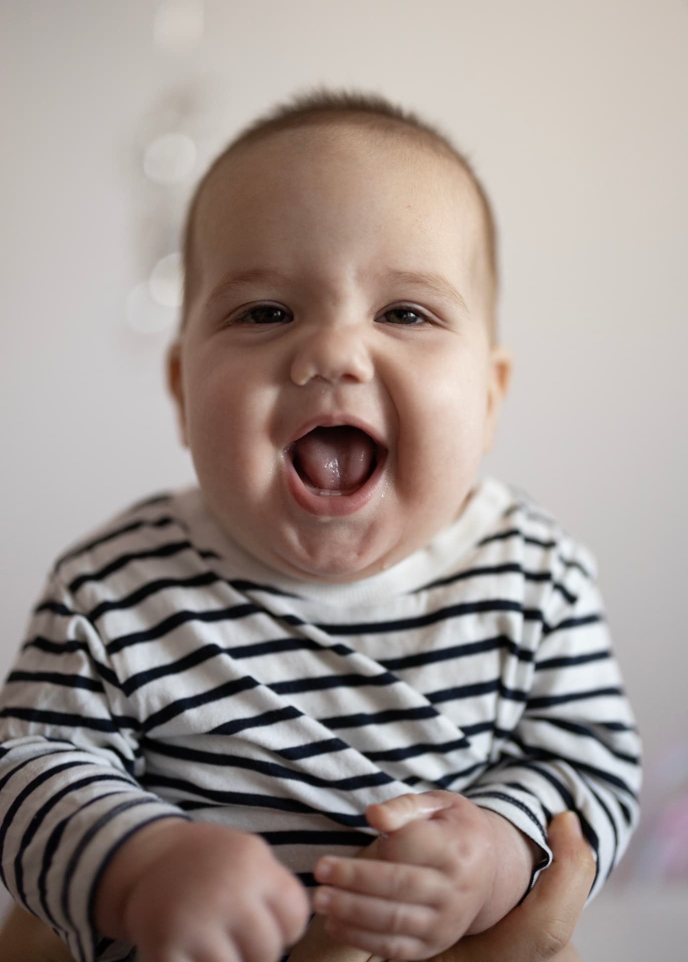 Laughing baby in a striped top, black and white portrait